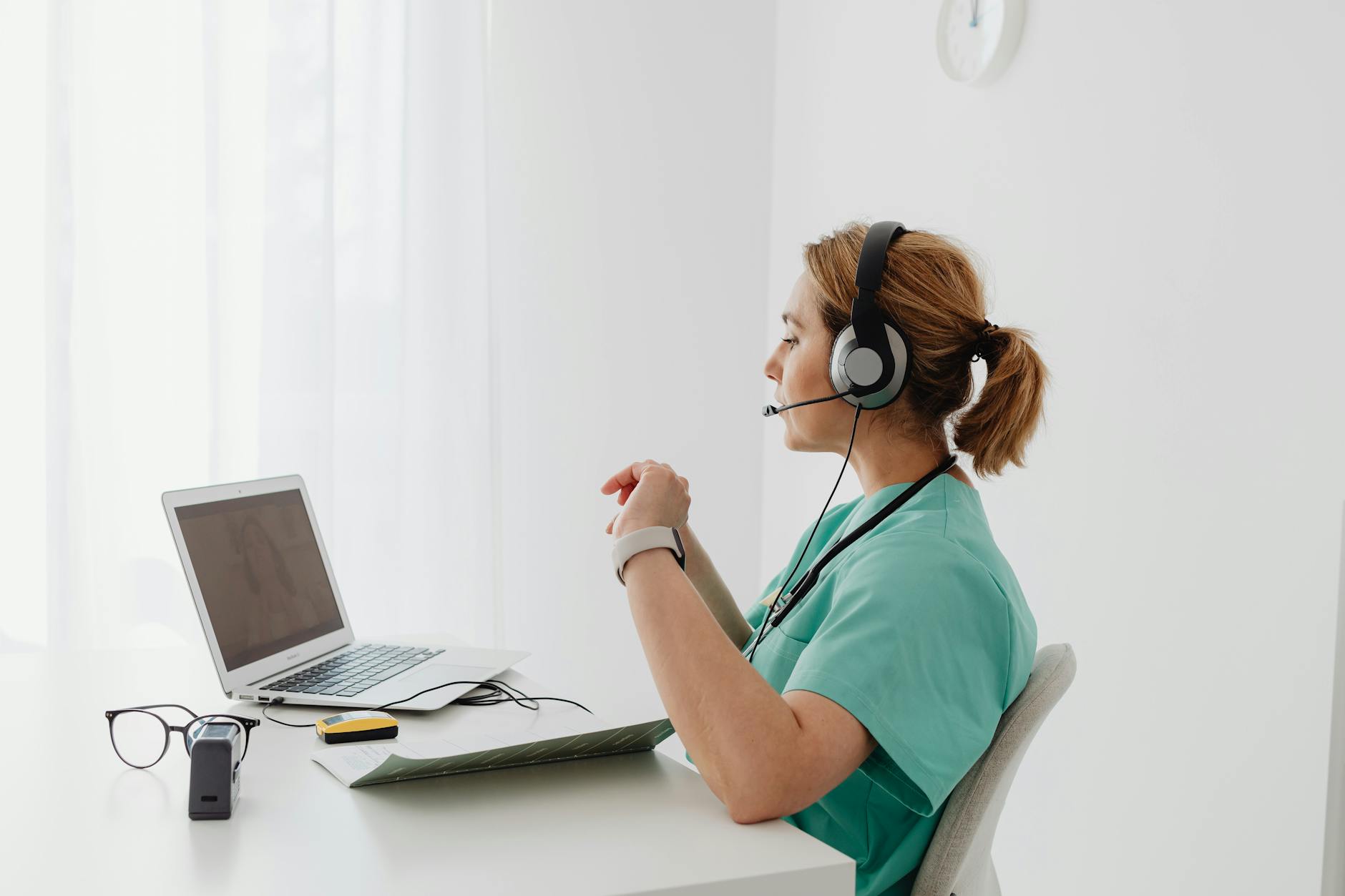 Female nurse practitioner in scrubs conducting a telehealth video appointment with patients online, California